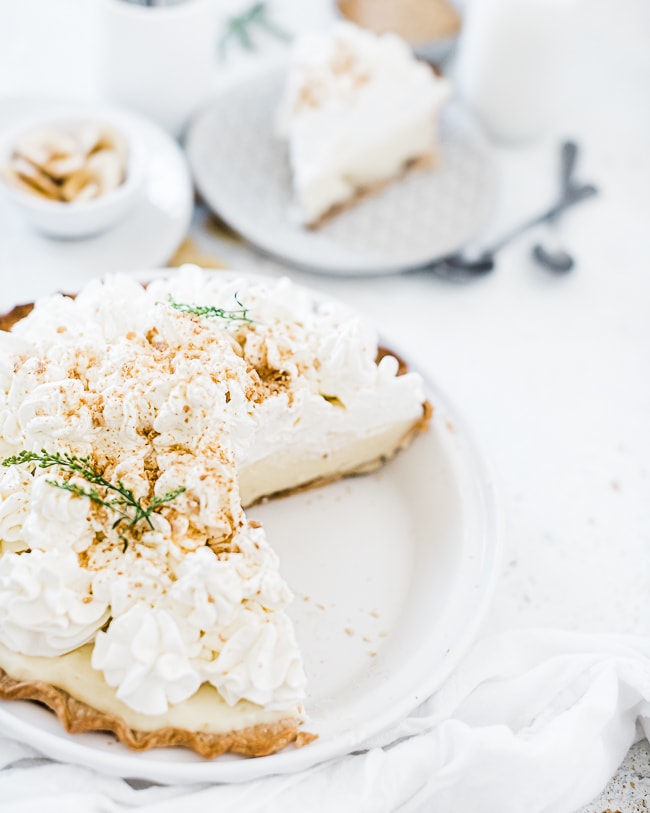 Easy banana cream pie recipe in a white pie plate. There is a large slice missing form the pie.
