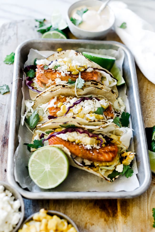 A ¾ view of blackened salmon tacos on a metal baking tray.