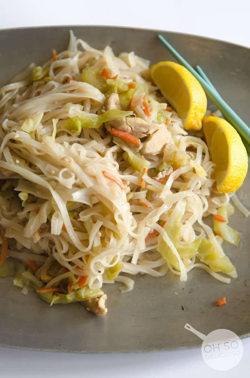 Pansit in dish with chopsticks with halved lemons to the side