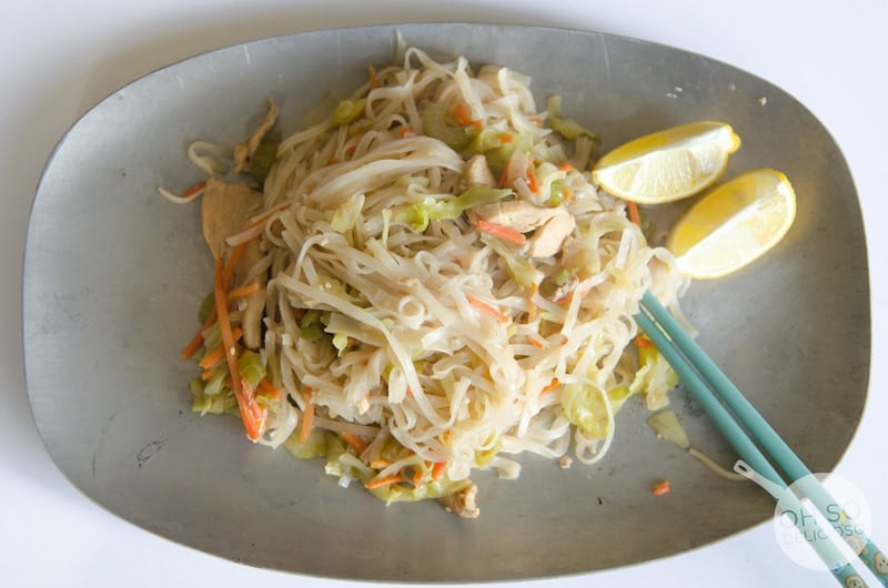 Pansit on plate with chop sticks with halved lemons