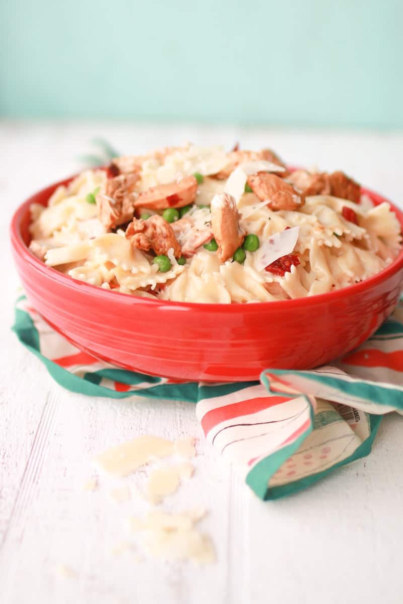 Bacon Chicken Pasta in bowl over patterned cloth with parmesan cheese shreddings to the side 
