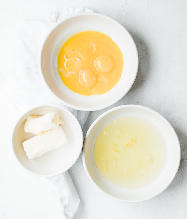 eggs separated in bowls and butter in a bowl