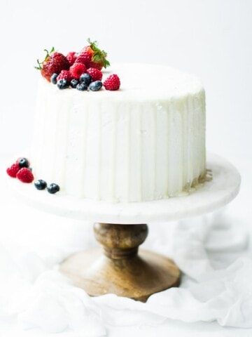 white cake with drips and fruit on top