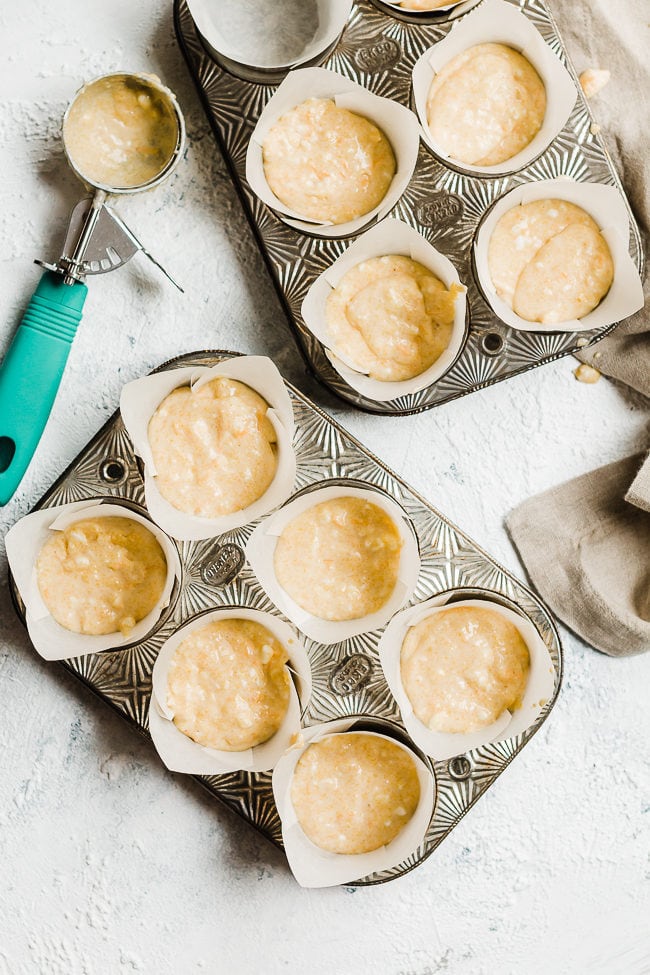Easy cornbread muffin batter in a metal muffin tin atop a grey napkin.