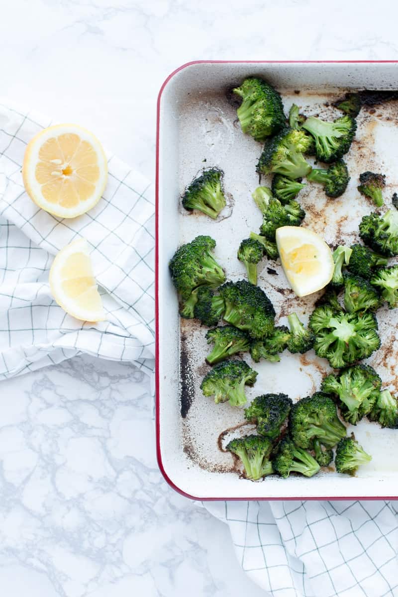 Roasted Broccoli with Cumin & Red Pepper on baking pan with lemon half