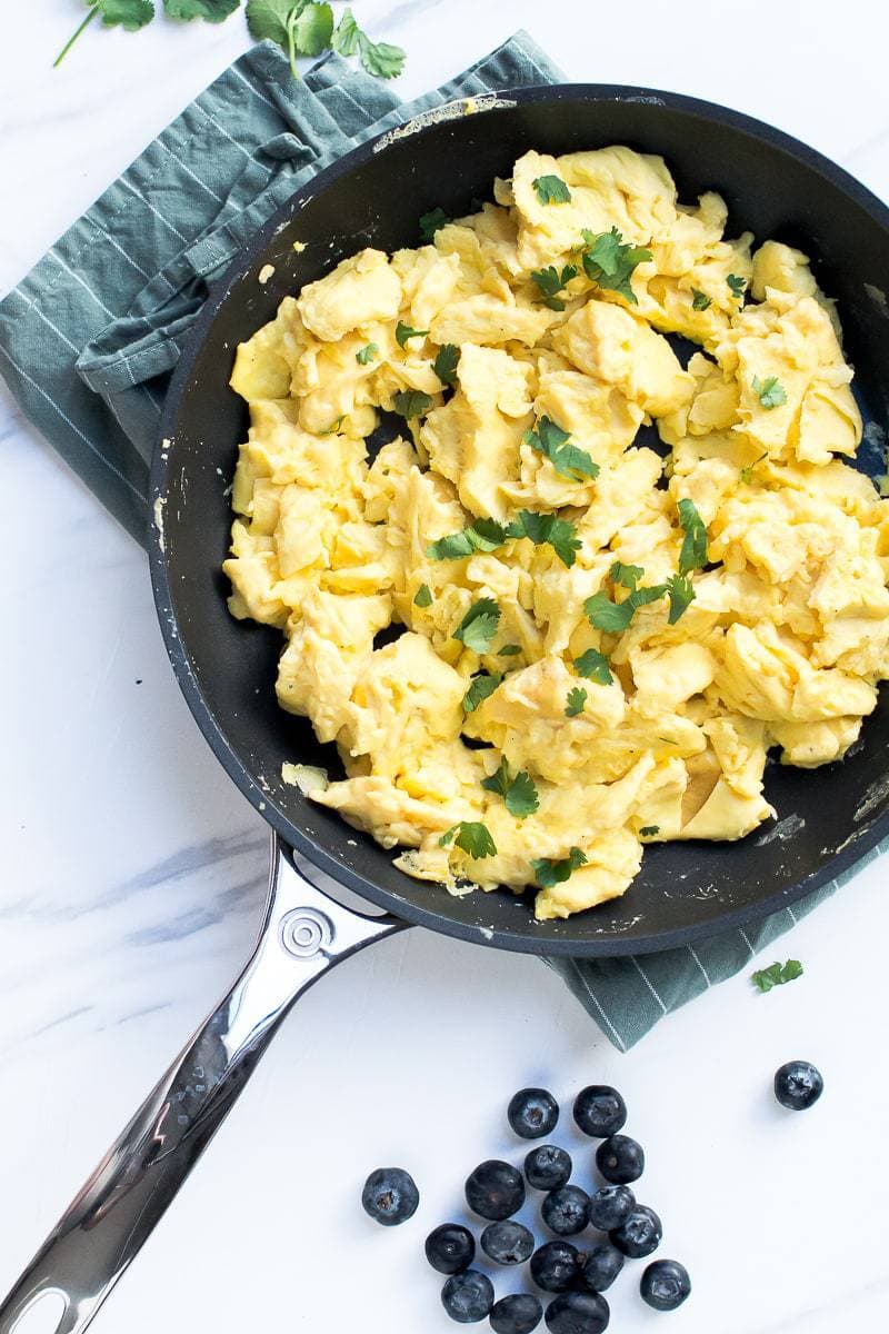 The Best Scrambled Eggs in a frying pan sitting on a marble surface