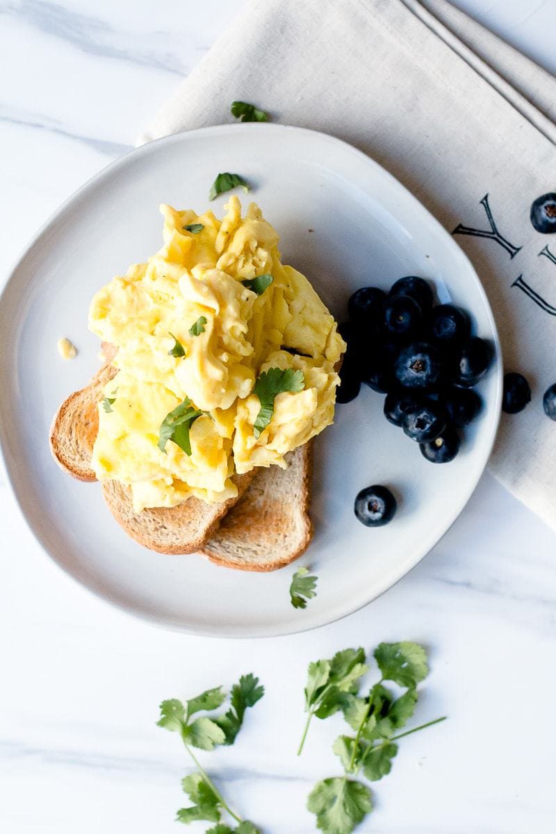 The Best Scrambled Eggs on a plate with toast and berries
