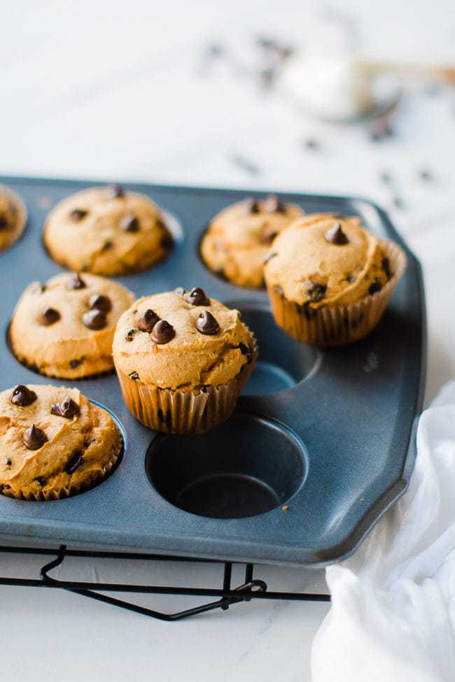 Pumpkin cake mix muffins with chocolate chips in a muffin tin.