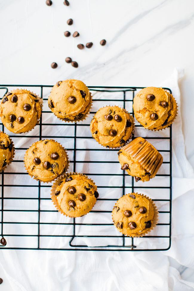 Pumpkin cake mix muffins with chocolate chips on a wire cooling rack.
