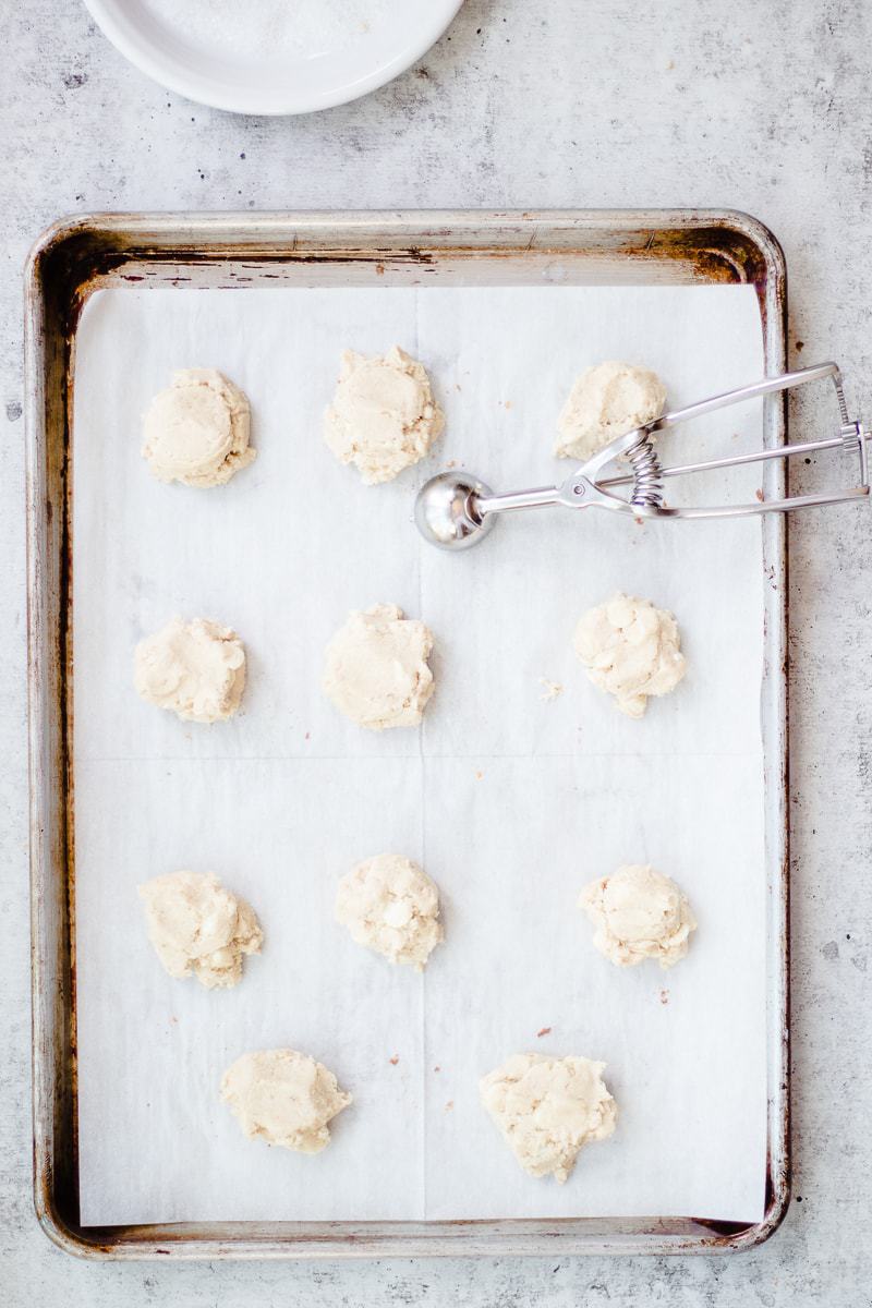 A baking tray filled with raw white chocolate chip cookies ready to be baked