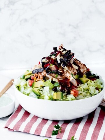 bbq chicken salad cpk in a white bowl with a red striped napkin and wooden utensils