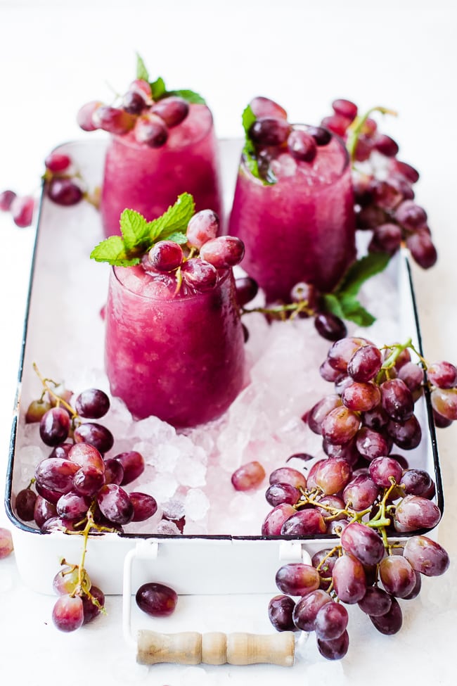 three cups of grape juice, ice, and grapes