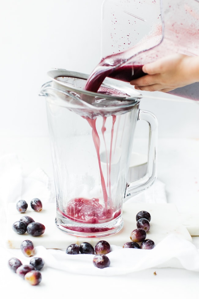 grape juice being poured into strainer into a picture