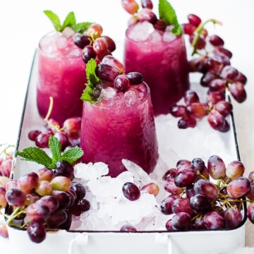 three cups of grape juice, ice, and grapes