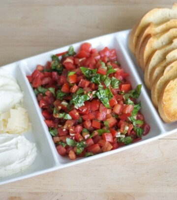 A plate filled with cheese, tomato and toast for making a bruschetta bar