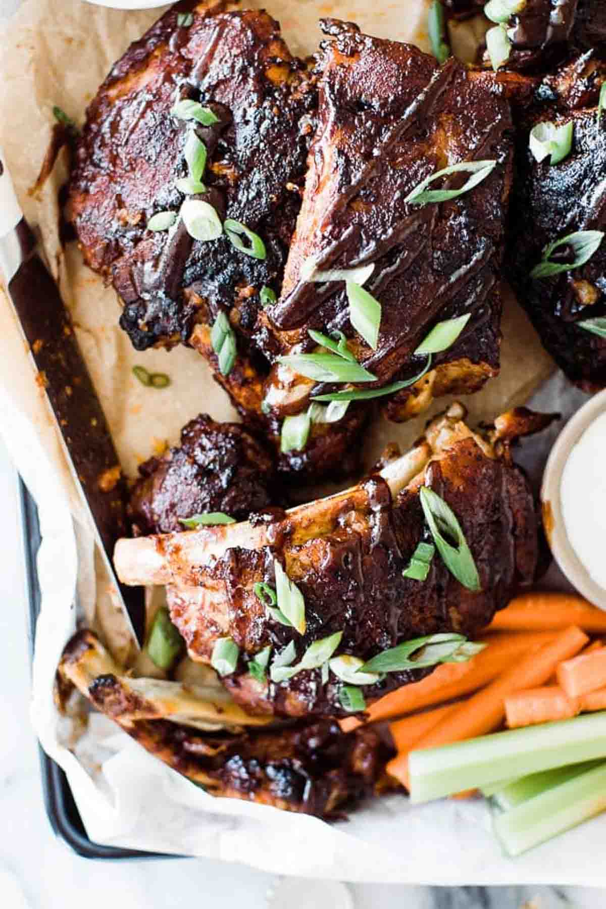 Sticky glazed instant pot ribs with green onions topped on top on a tray.