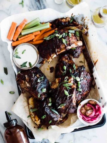 sticky glazed ribs with green onions topped on top on a tray