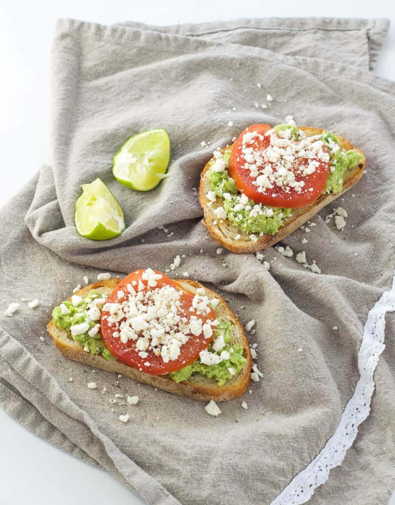 Avocado Feta Toast with tomatoes and lime wedges