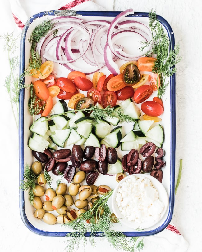 purple onion, tomatoes, cucumbers, olives feta cheese or topping hummus to make loaded greek hummus on a tray