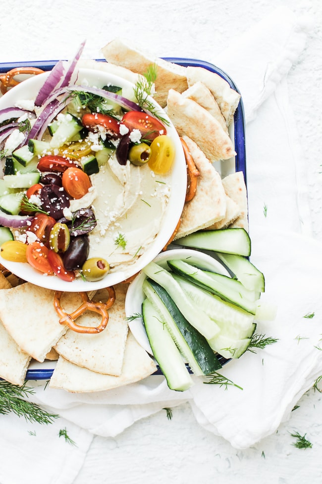 purple onion, tomatoes, cucumbers, olives feta cheese or topping hummus to make loaded greek hummus on a tray