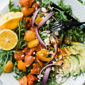 plate of salad with tomatoes lemon and avocado