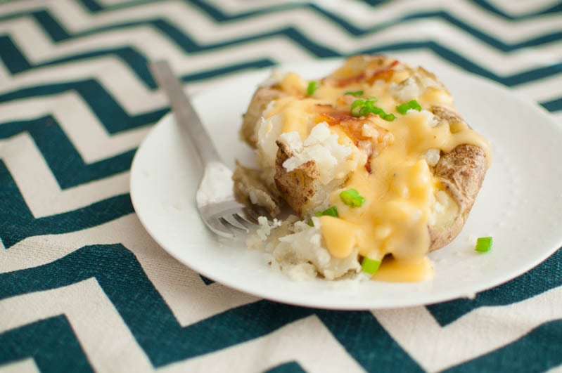 close up of baked potato with cheese sauce on top