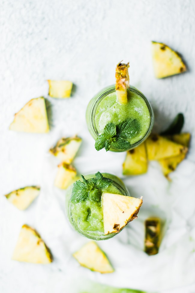 two jars of green smoothie with mint and pineapple garnish