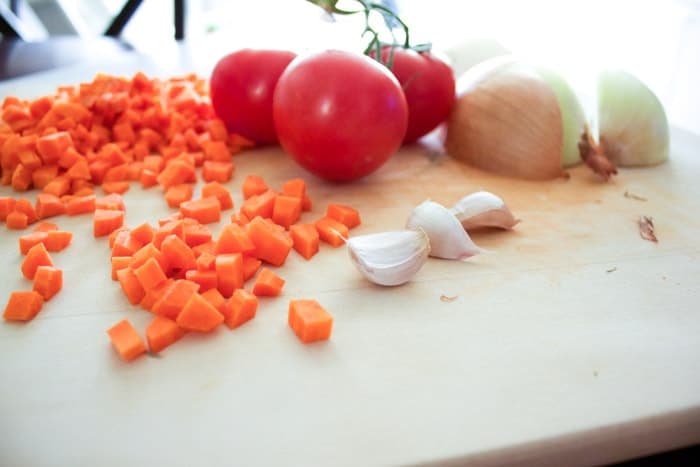 carrots, tomatoes, garlic and onions on wooden cutting board
