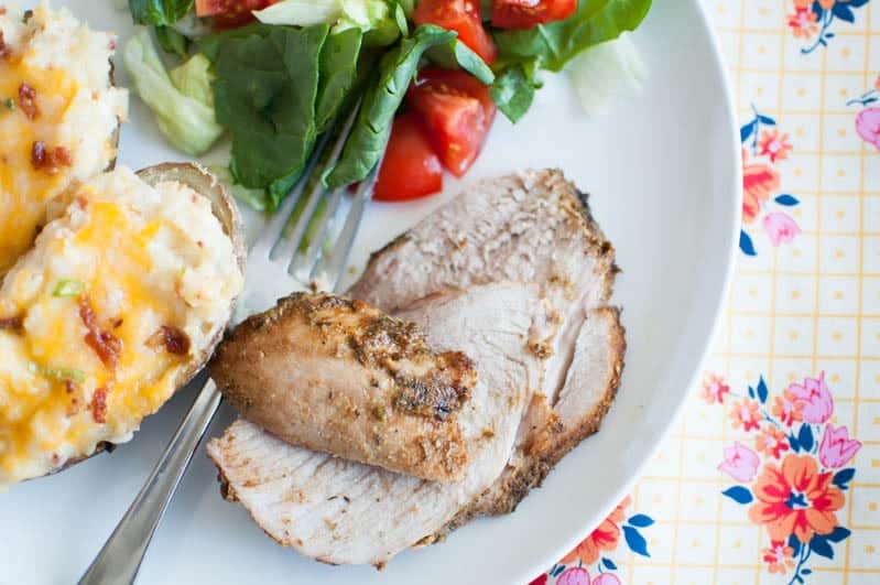 herb pork on plate with baked potato and salad 