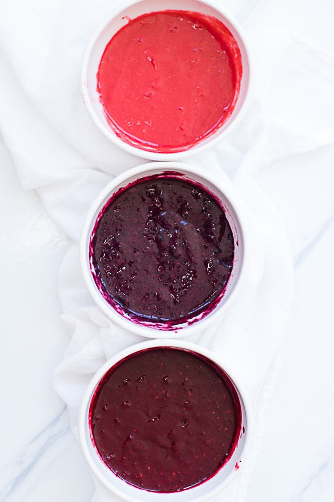 raspberry, blueberry and blackberry puree in three different bowls for making triple berry popsicles