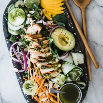 salad with avocado, mango, chicken and veggies on black platter