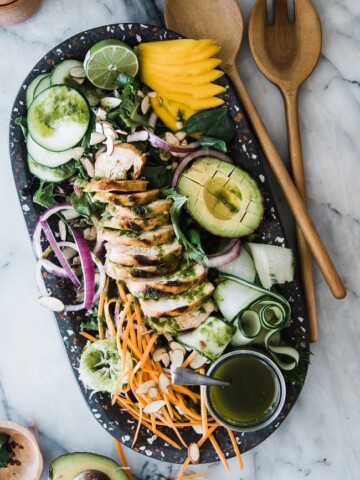salad with avocado, mango, chicken and veggies on black platter