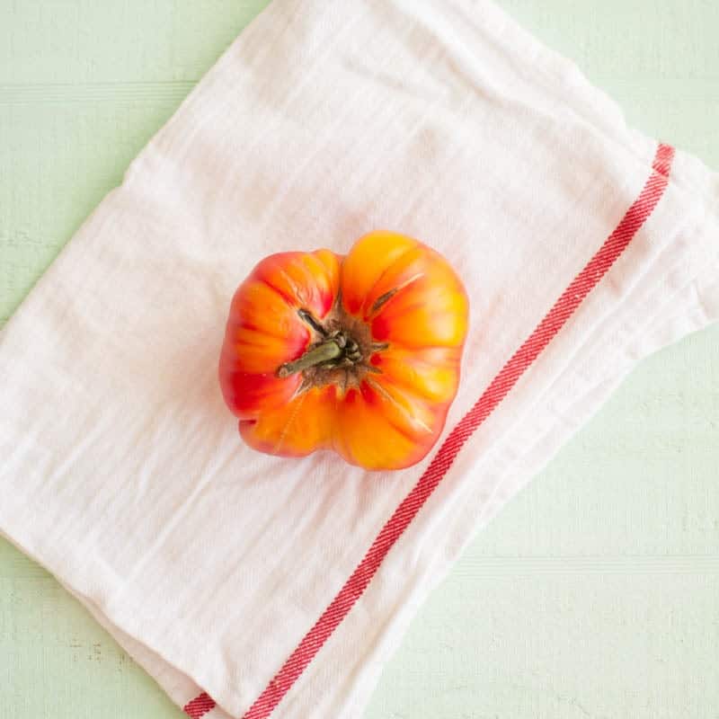 A large tomato on a white dish cloth