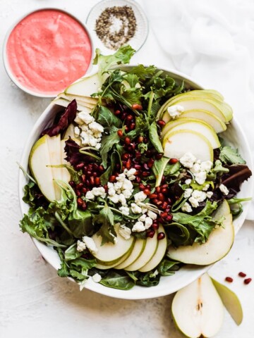 Pear pomegranate salad in a white bowl.