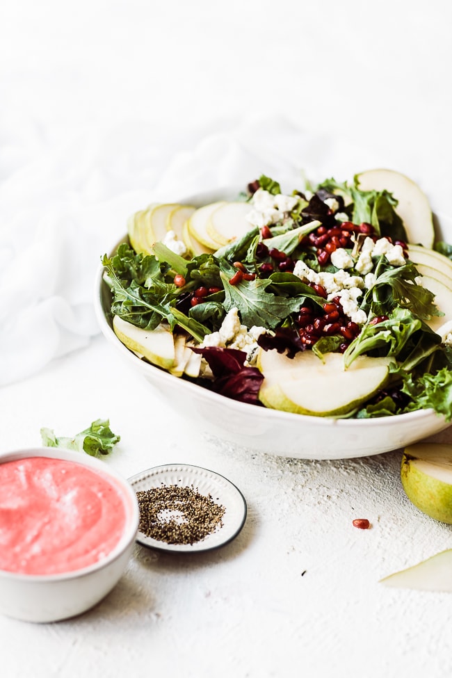 Pear pomegranate salad in a white bowl.