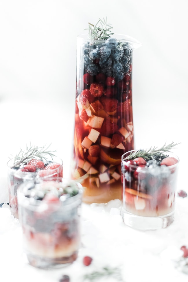 Mock winter sangria in a glass pitcher, with a single serving to the side in a whiskey glass.