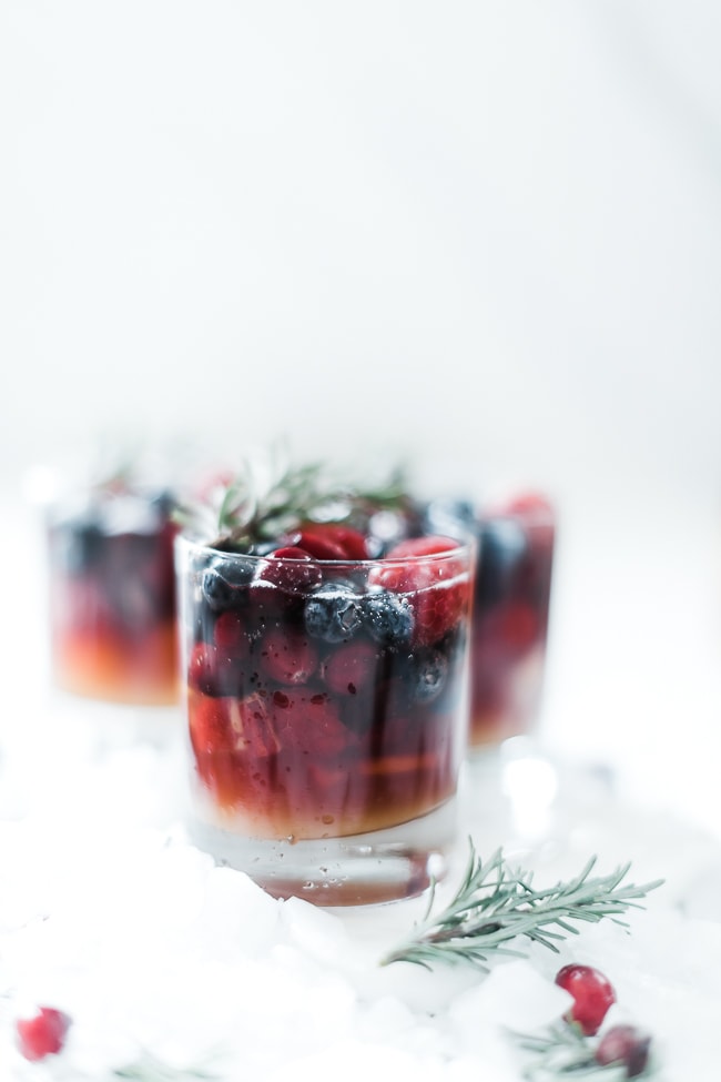 Mock winter sangria in whisky glasses, garnished with rosemary on a bed of ice.