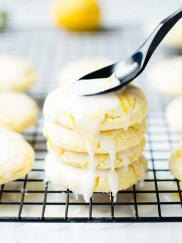a stack of lemon cookies with glaze being drizzled over