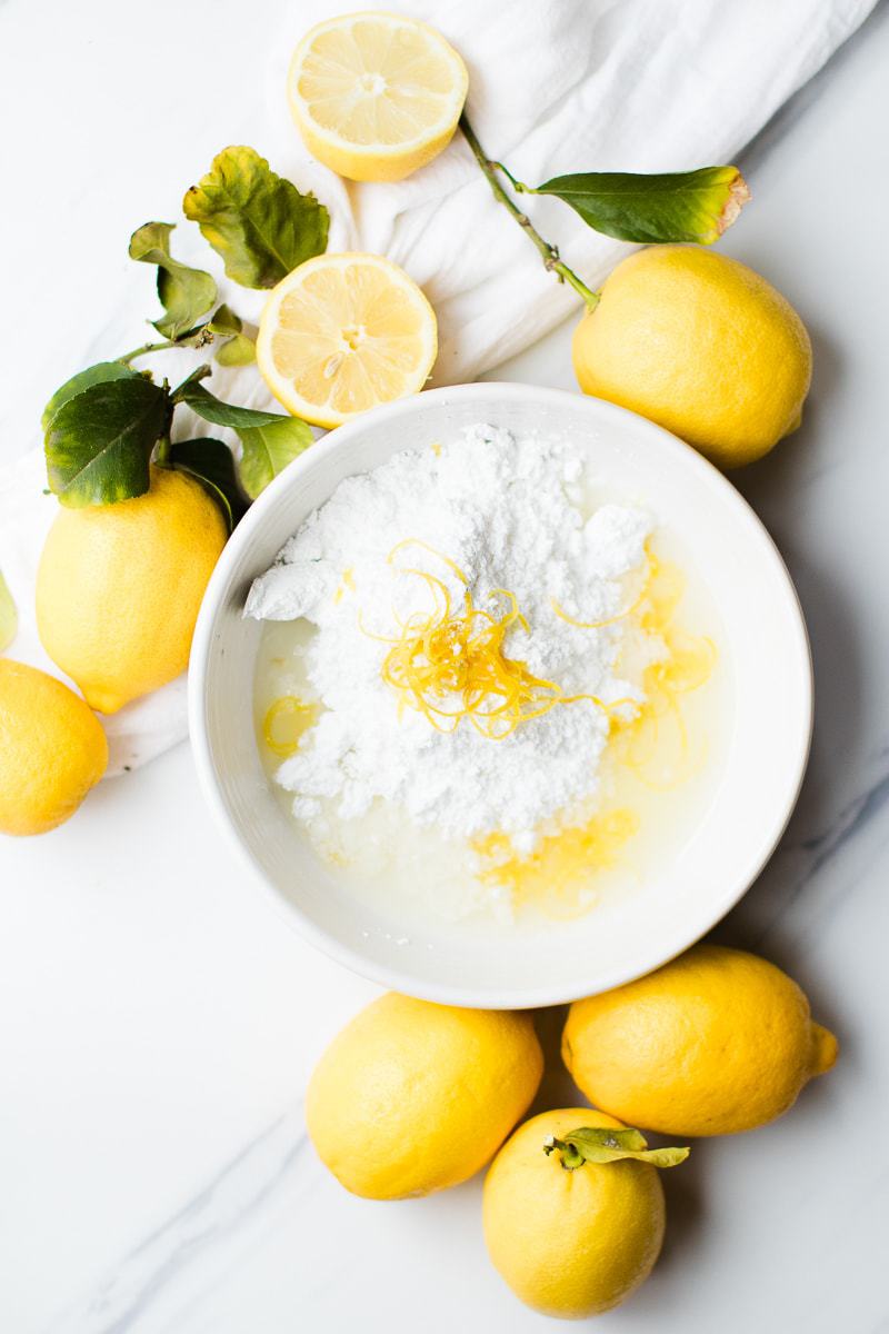 lemon cookie glaze ingredients in bowl surrounded by fresh lemons