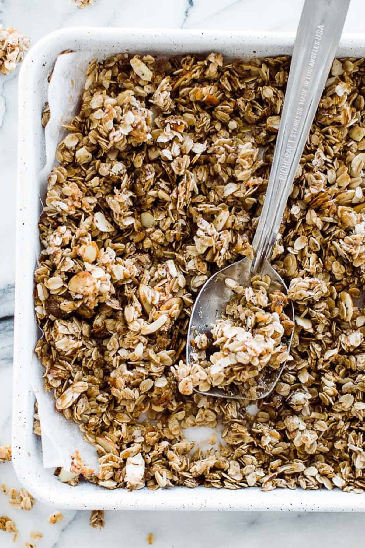 Honey granola on a jelly roll pan lined with parchment paper.