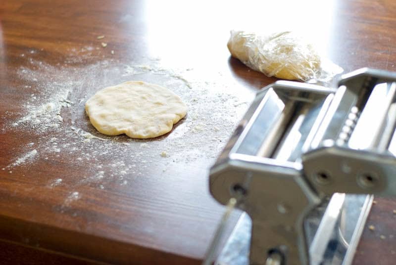 noodle dough on wooden table, over layer of flour, with pasta cutter