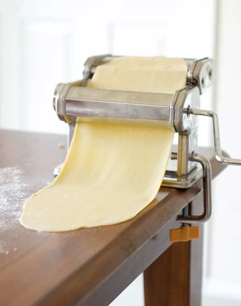 noodle dough going through pasta roller