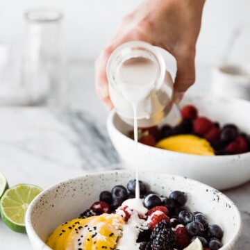 coconut syrup pouring over bowl of fruit and quinoa