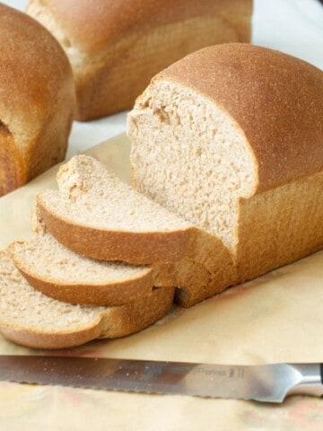 A side shot of a loaf of 100% whole wheat bread cut into slices