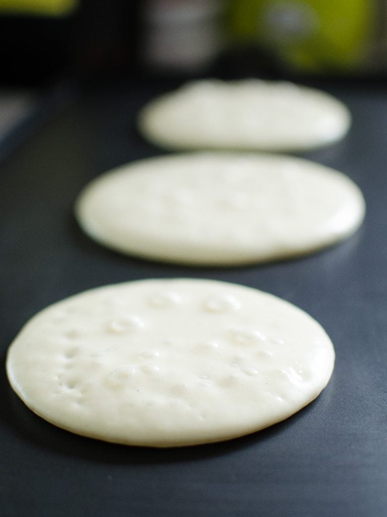 pancake batter being cooked on a griddle