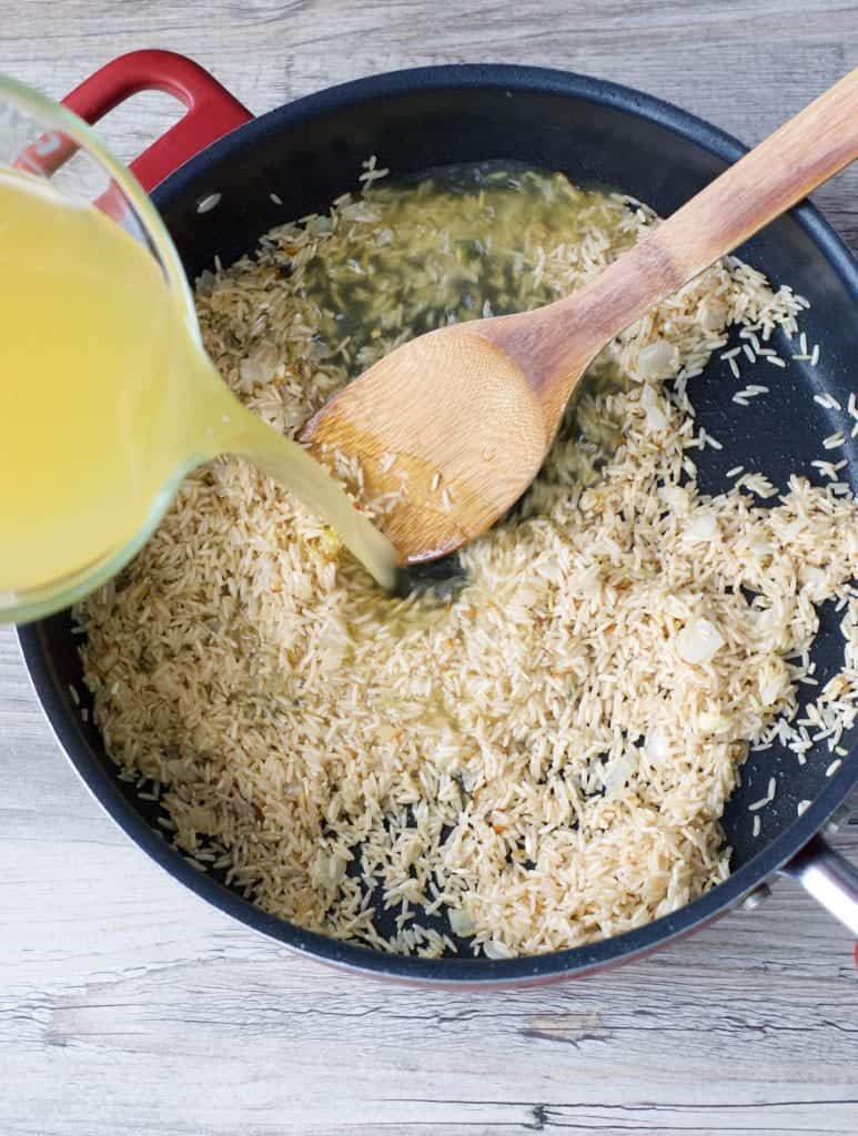 pilaf being made in a pan with stock