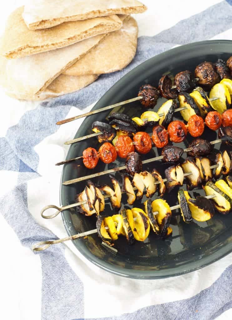 grilled vegetables on skewers next to pita bread