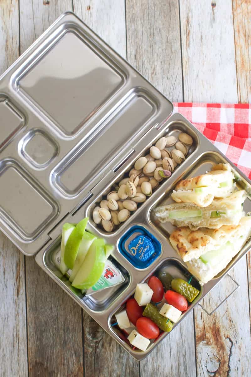 Planet Box Lunch- inside are pistachios, sliced green apples, pickle-tomato-cheese skewer, and cucumber sandwich