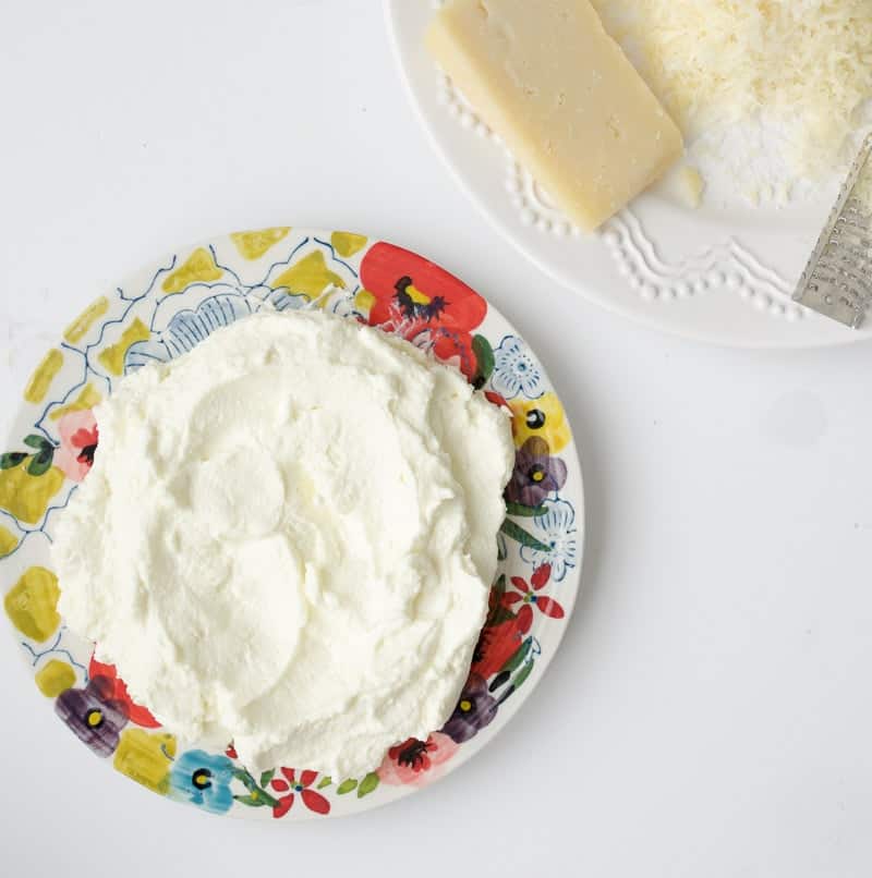 An overhead shot of homemade ricotta on a patterned plate used to make ricotta pizza