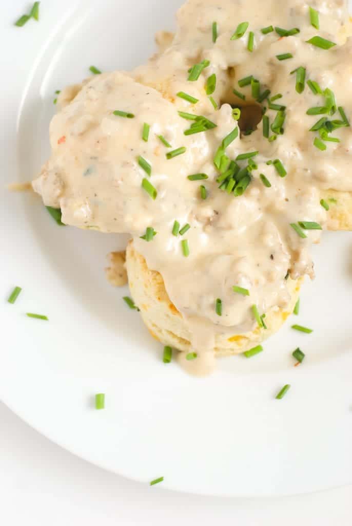 An overhead shot cheese biscuits and gravy topped with chopped chives
